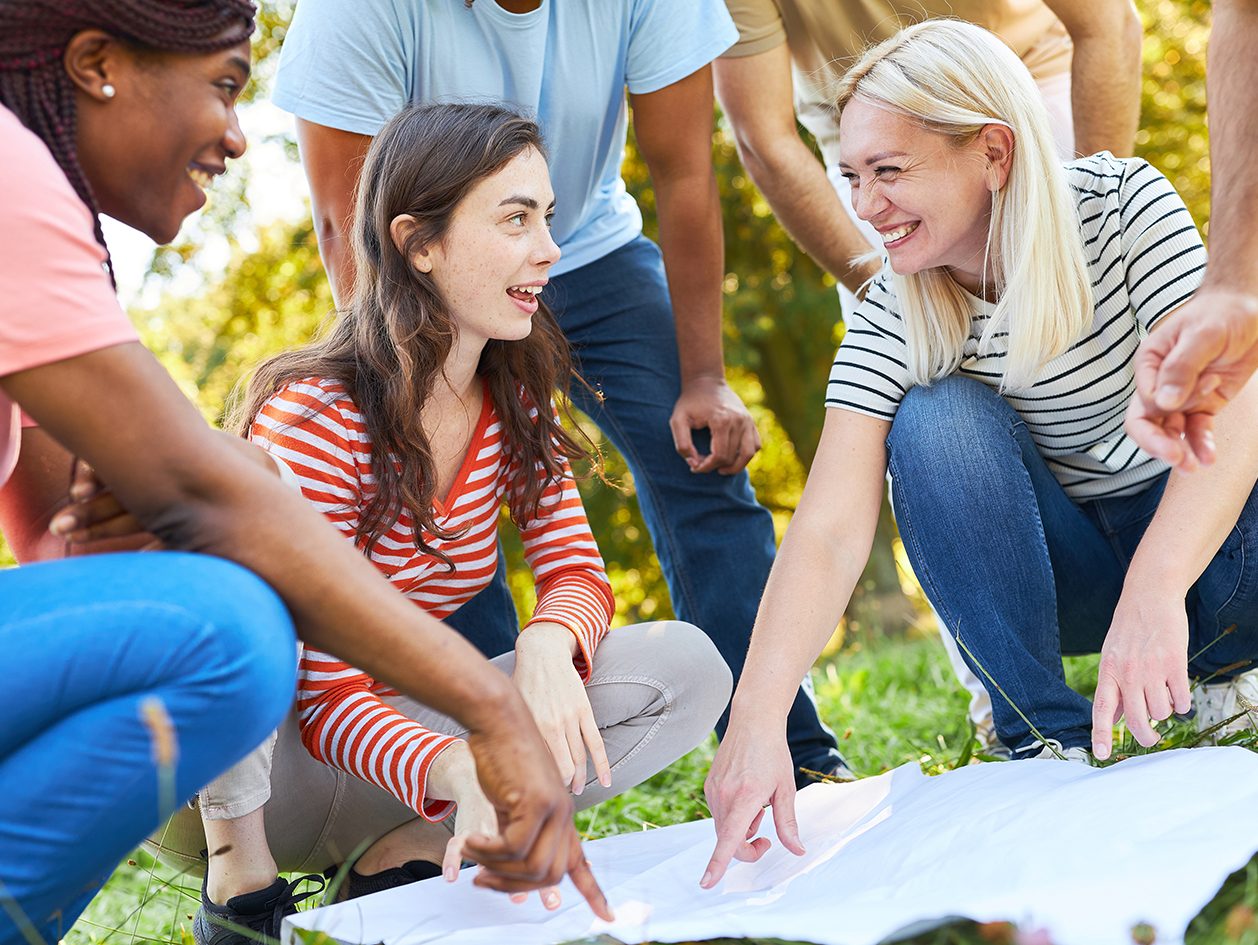 Image of a group of people pointing to a piece of paper on the ground.