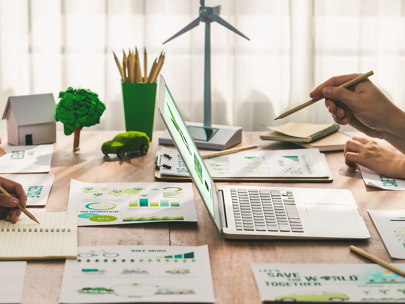 Image of someone working at a laptop and charts around the desk.